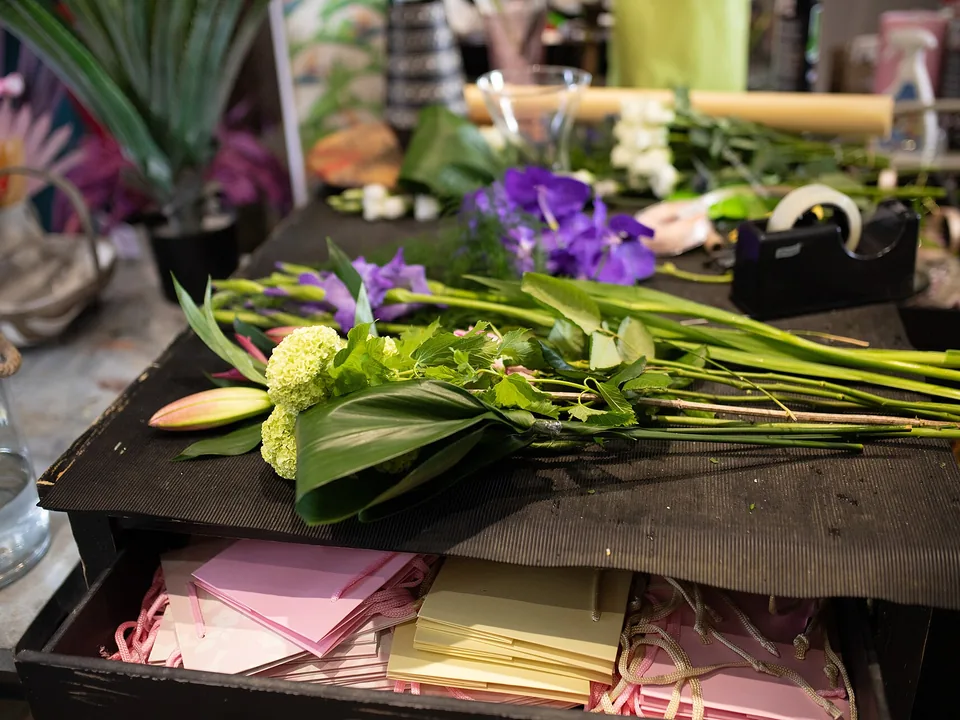 Mesa de trabajo con flores y follaje listos para armar